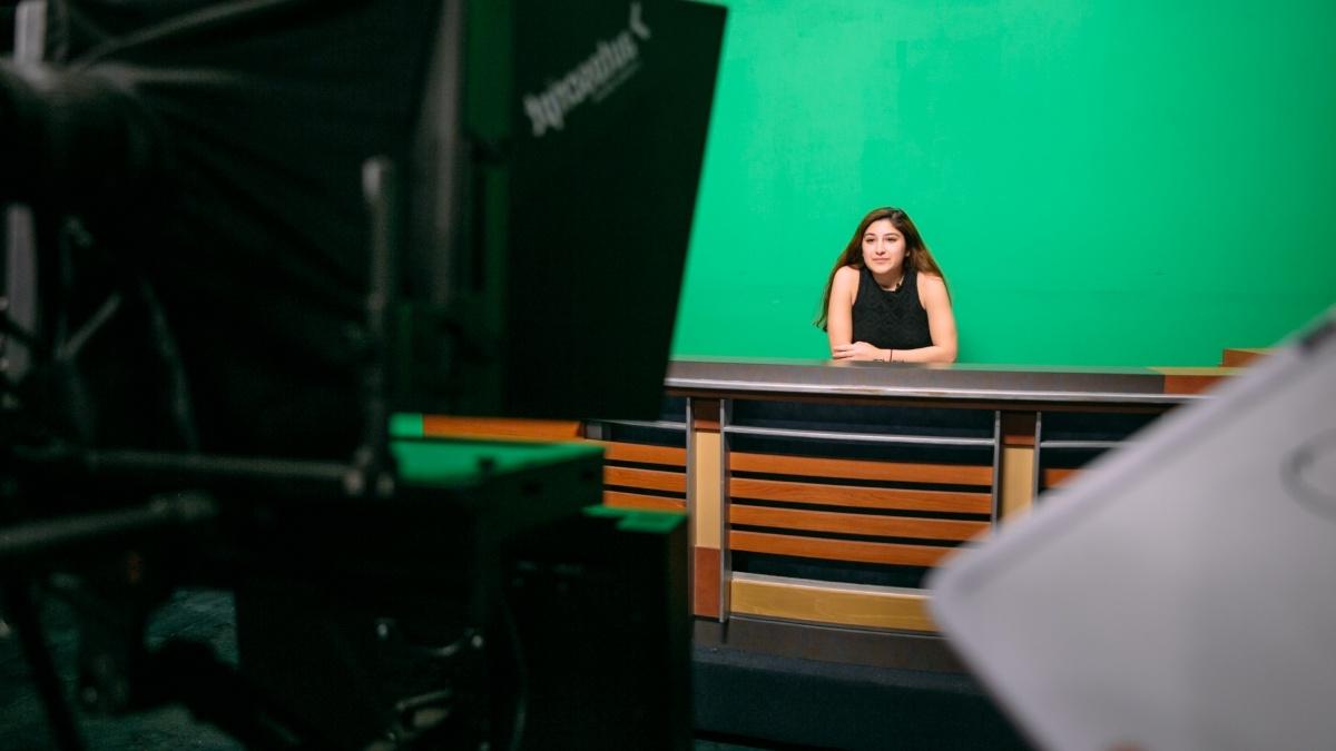 A student is filmed in front of a green screen for TigerTV